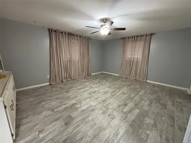 an empty room with wooden floor and chandelier fan