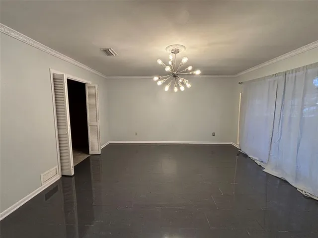 an empty room with a chandelier fan and wooden floor
