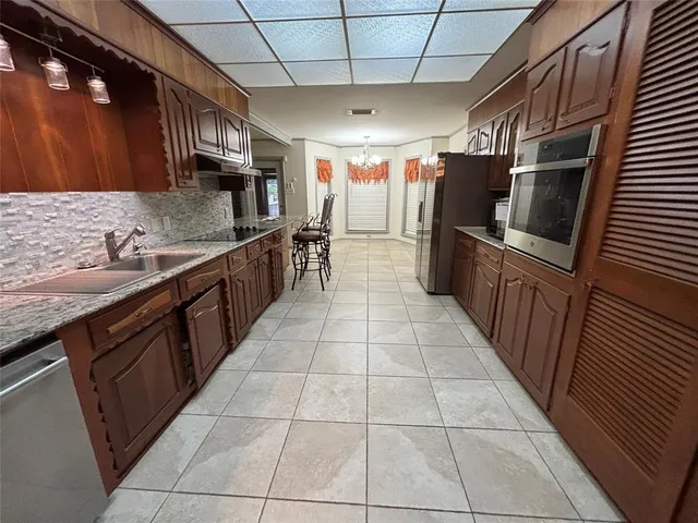 a large kitchen with a stove top oven a sink a counter space and cabinets