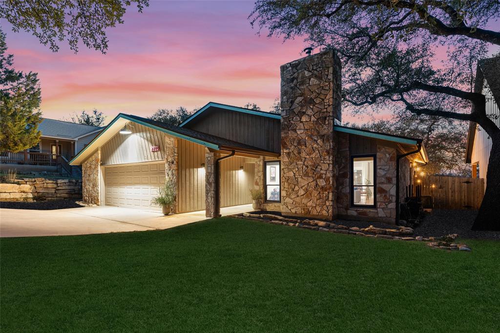 2210 Red Fox Road Austin, TX 78734 - Photo 3 of 40 Dramatic stonework and modern wood siding create compelling curb appeal beneath a colorful twilight sky.