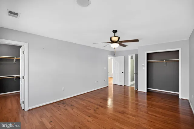 an empty room with wooden floor fan and windows