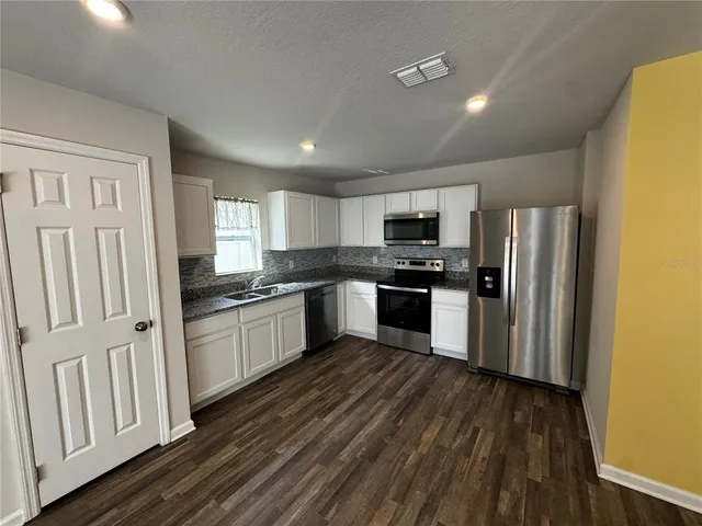 a kitchen with granite countertop a refrigerator oven a sink dishwasher and a stove with wooden floor