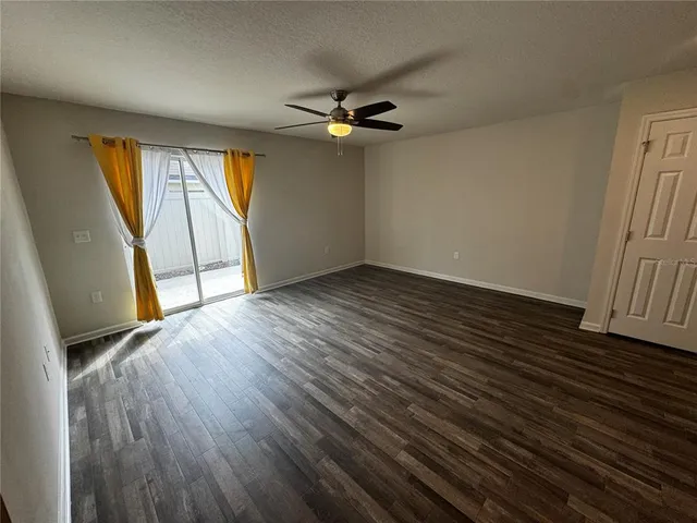 an empty room with wooden floor fan and windows