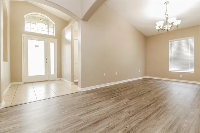an empty room with wooden floor cabinet and windows