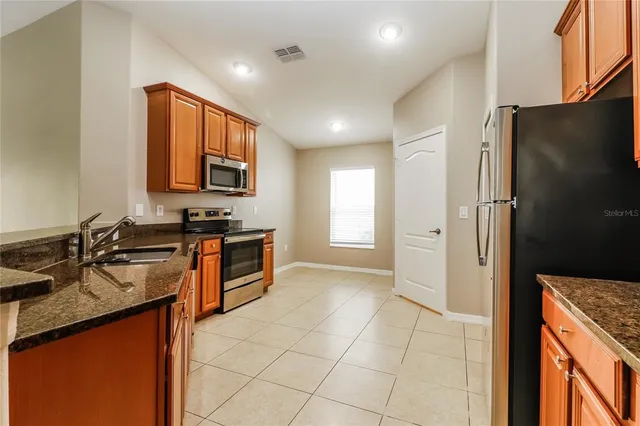 a kitchen with stainless steel appliances granite countertop a stove a sink and a refrigerator