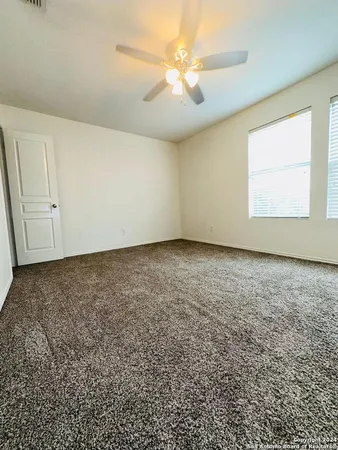 an empty room with a window and a ceiling fan