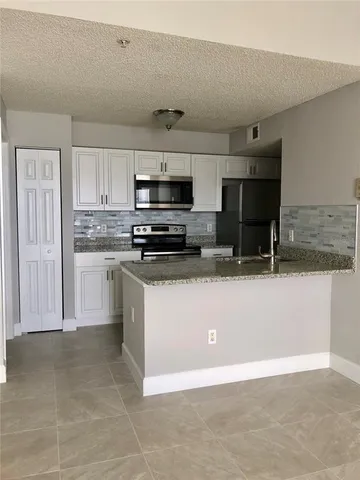 a kitchen with stainless steel appliances granite countertop a refrigerator and a stove top oven