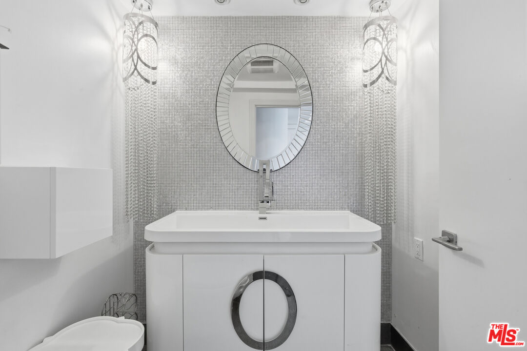 121 South Canon Drive, Unit PH 401 Beverly Hills, CA 90212 - Photo 14 of 31 a bathroom with a toilet a sink and a mirror