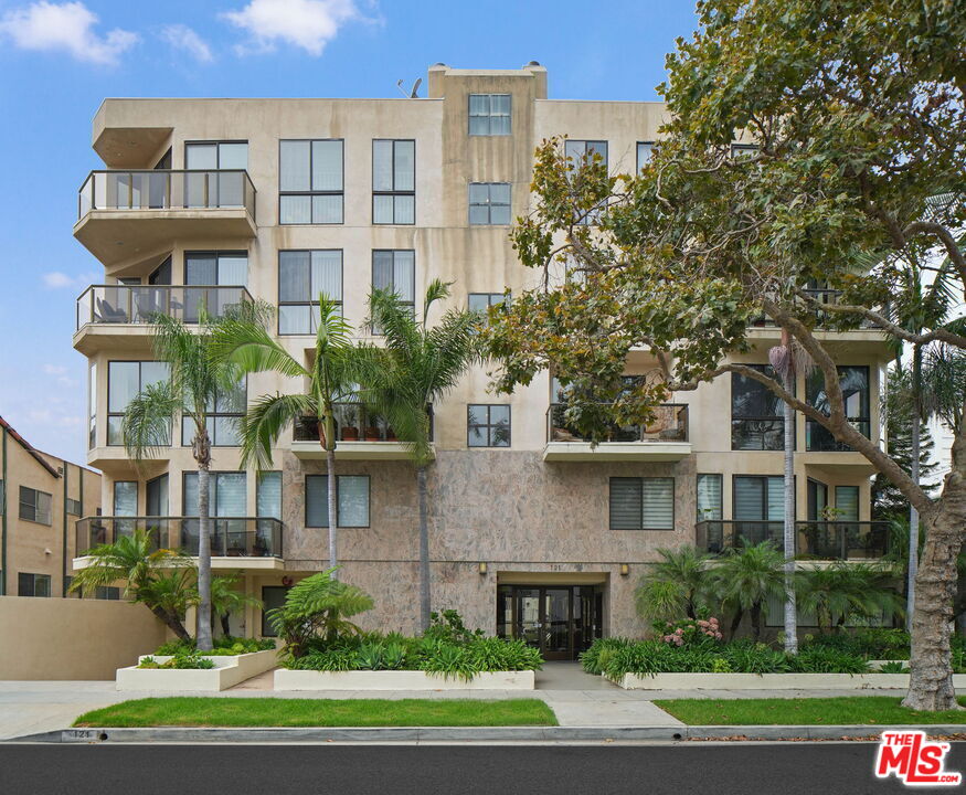 121 South Canon Drive, Unit PH 401 Beverly Hills, CA 90212 - Photo 30 of 31 a front view of a residential apartment building with a yard