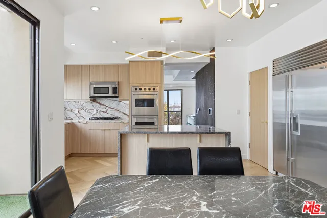 a kitchen with stainless steel appliances kitchen island granite countertop a refrigerator and a stove top oven