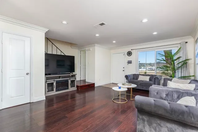 a living room with furniture a flat screen tv and kitchen view