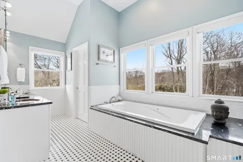 a bathroom with a granite countertop sink and a large mirror next to a window