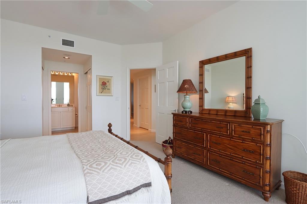 60 Seagate Drive, Unit 704 Naples, FL 34103 - Photo 18 of 28 a bedroom with a bed and a dresser