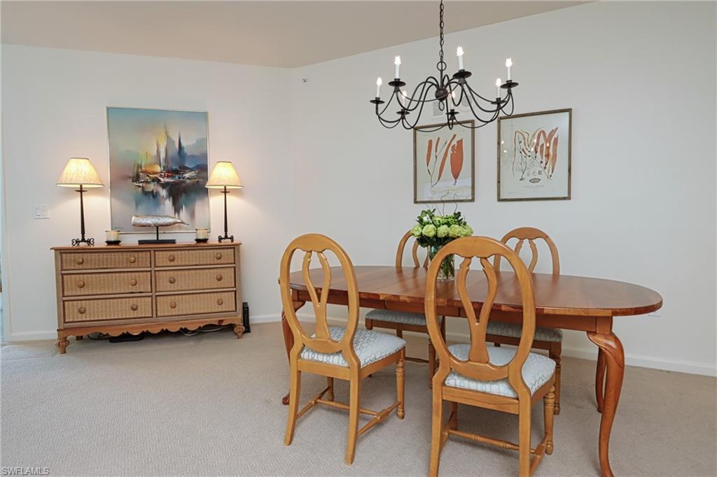 60 Seagate Drive, Unit 704 Naples, FL 34103 - Photo 9 of 28 a dining room with furniture and chandelier
