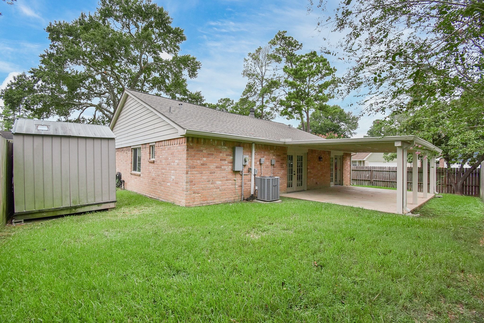 17330 Modbury Drive Spring, TX 77379 - Photo 27 of 30 Spacious backyard with lush green lawn, bordered by a wooden fence and featuring a practical storage shed, perfect for gardening and outdoor activities.