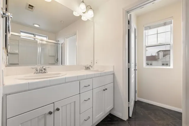 a bathroom with double vanity sink a mirror and a shower