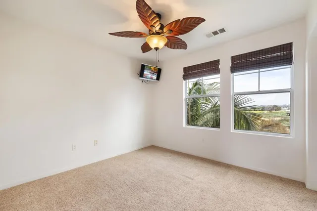 an empty room with windows and ceiling fan