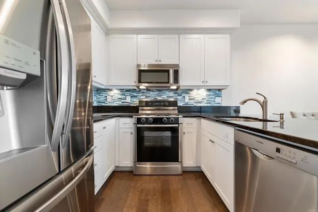 a kitchen with stainless steel appliances granite countertop a stove a refrigerator and a sink
