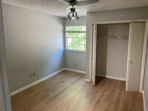 an empty room with wooden floor chandelier and windows