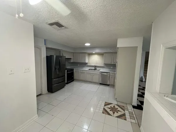 a kitchen with stainless steel appliances kitchen island granite countertop a refrigerator and a sink