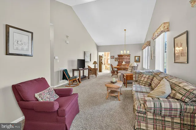 a living room with furniture kitchen view and a chandelier