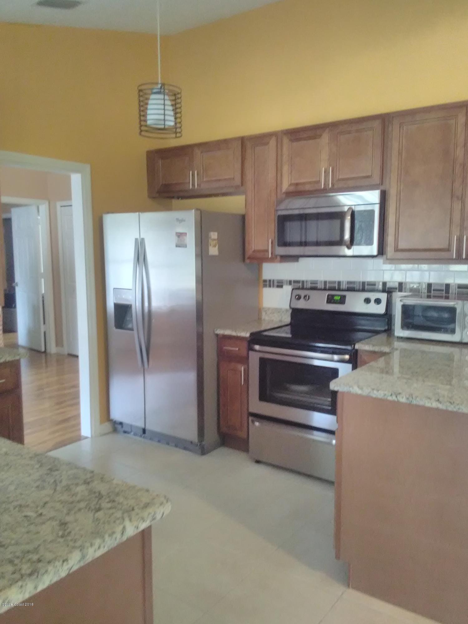 231 Rheine Road Northwest Palm Bay, FL 32907 - Photo 4 of 10 a kitchen with stainless steel appliances granite countertop a refrigerator and a stove top oven
