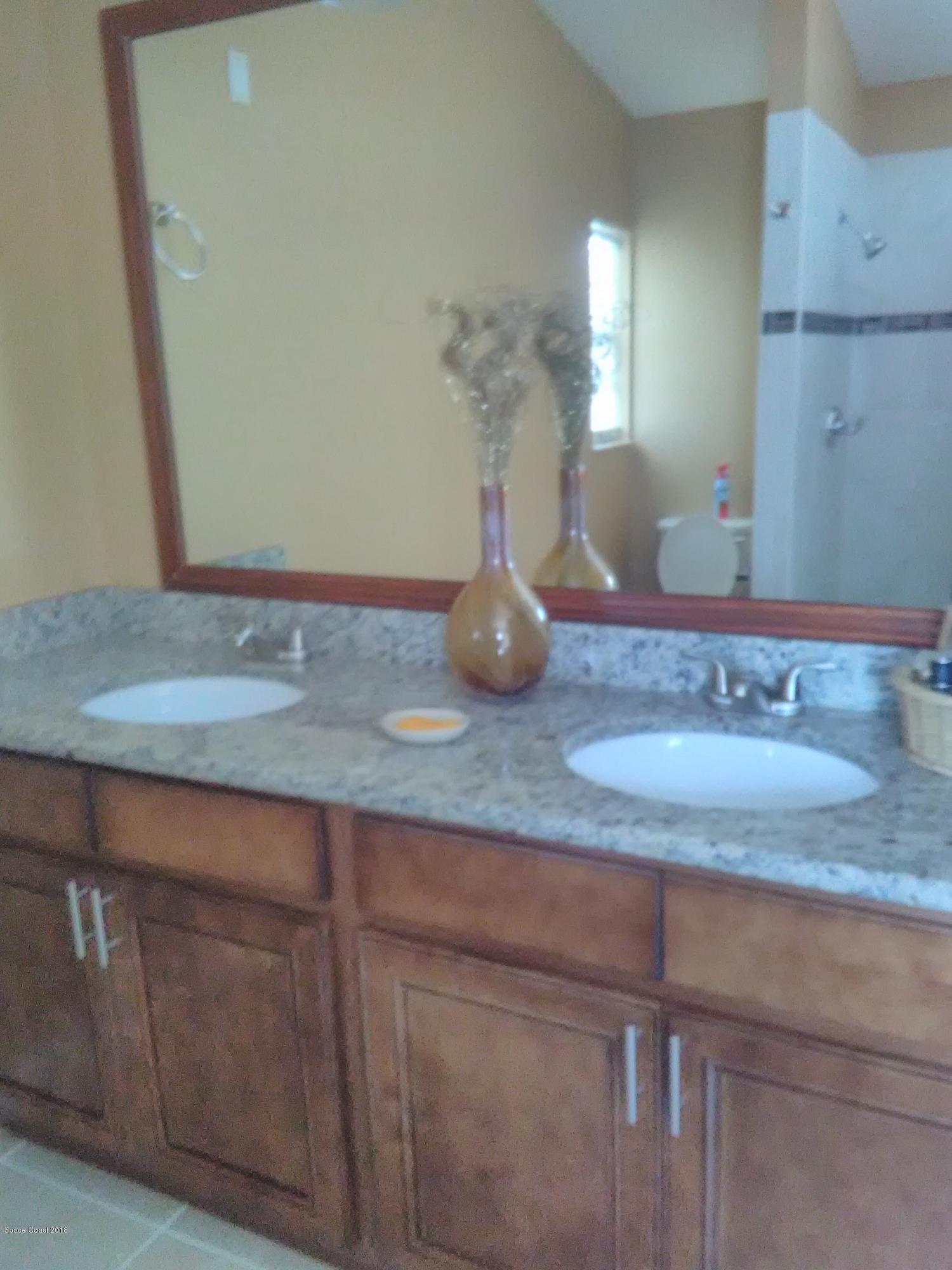 231 Rheine Road Northwest Palm Bay, FL 32907 - Photo 9 of 10 a bathroom with a granite countertop sink and a mirror