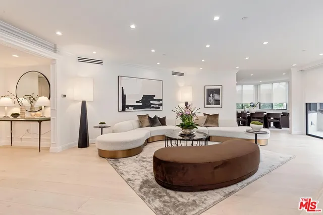 a living room with furniture a clock and a view of kitchen