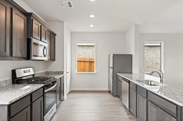 a kitchen with stainless steel appliances granite countertop a sink stove and refrigerator