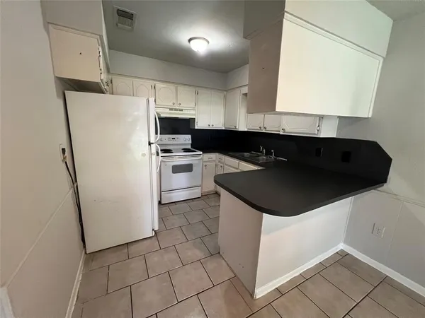 a kitchen with a sink a refrigerator and cabinets