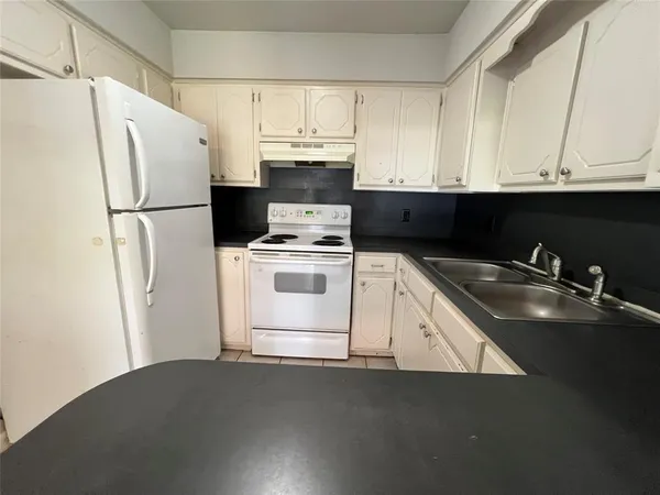 a kitchen with a refrigerator sink and cabinets
