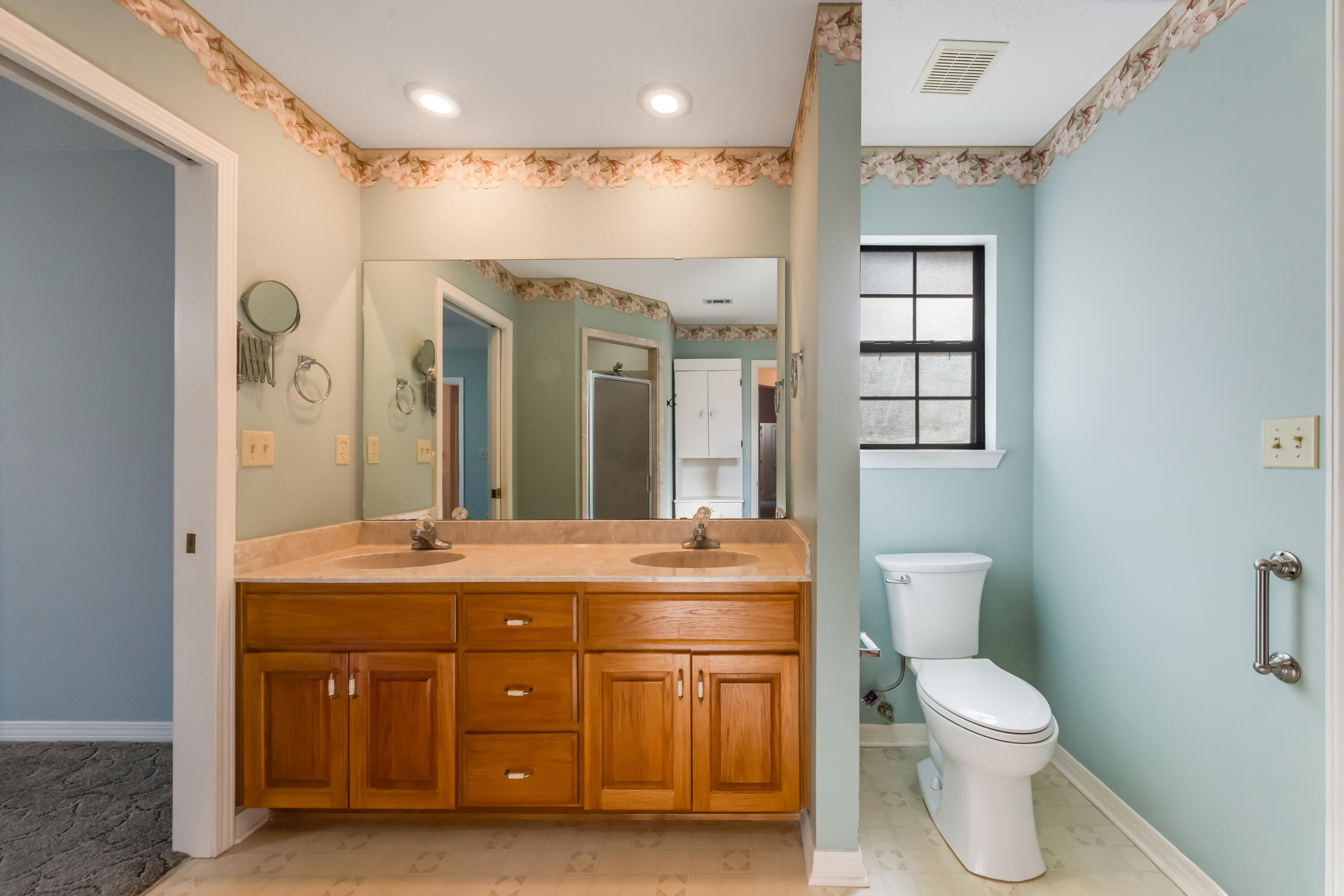 5965 Oak Hill Road Crestview, FL 32536 - Photo 18 of 44 a spacious bathroom with a granite countertop toilet a sink and a large mirror