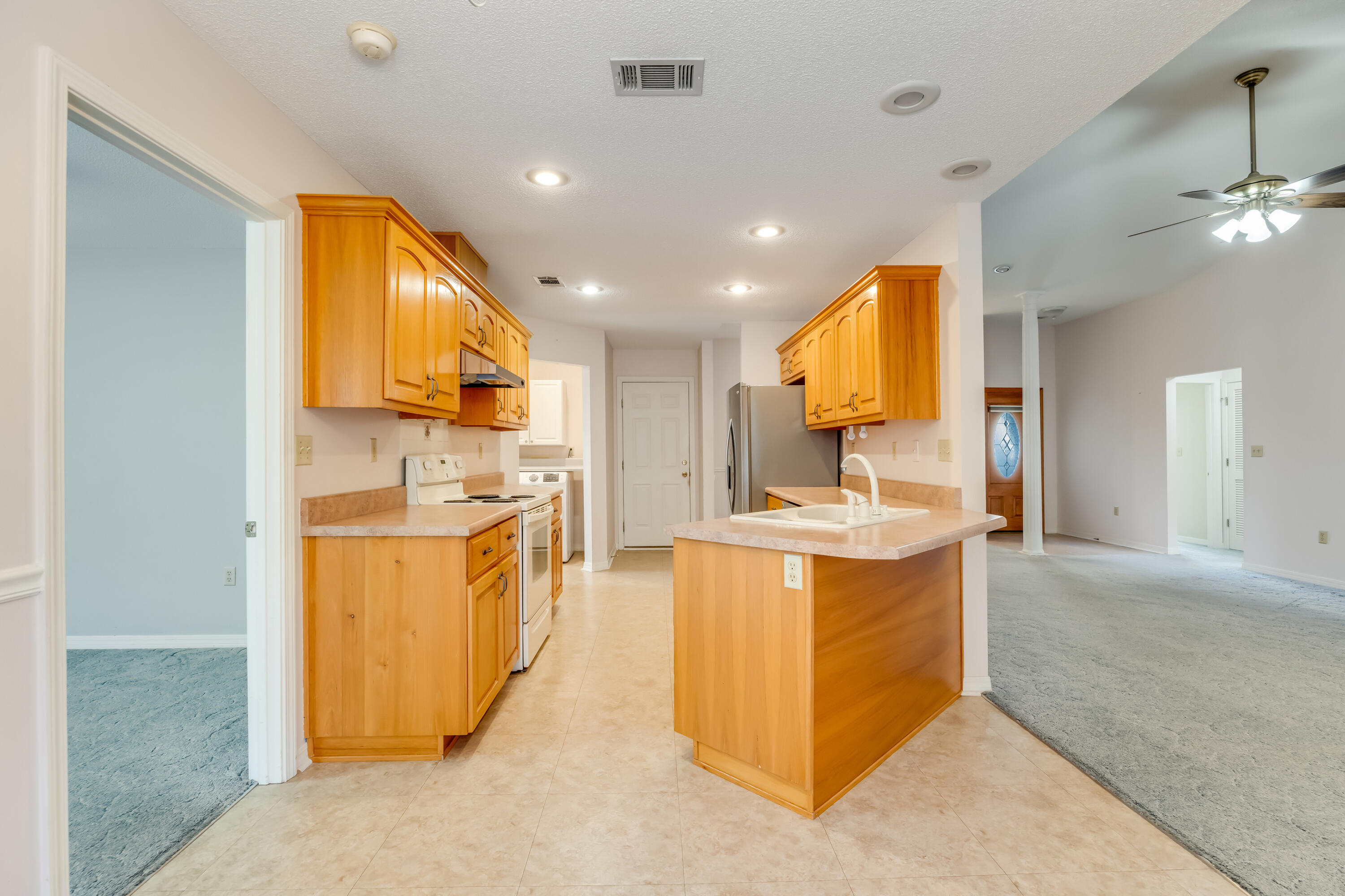 5965 Oak Hill Road Crestview, FL 32536 - Photo 10 of 44 a large kitchen with stainless steel appliances a stove a sink a refrigerator and blue cabinets with wooden floor