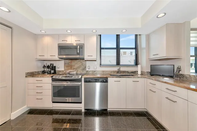 a kitchen with stainless steel appliances a stove a sink and white cabinets