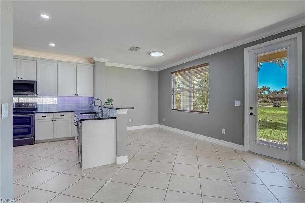 1654 Double Eagle Trail Naples, FL 34120 - Photo 3 of 48 Kitchen with white cabinetry, backsplash, kitchen peninsula, and appliances with stainless steel finishes
