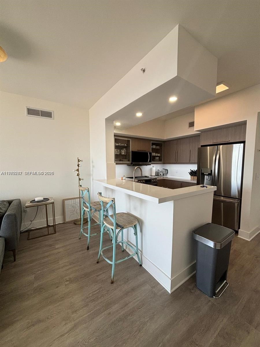 888 Douglas Road, Unit 1002 Coral Gables, FL 33134 - Photo 12 of 34 a room with stainless steel appliances kitchen island granite countertop a table chairs sink and cabinets