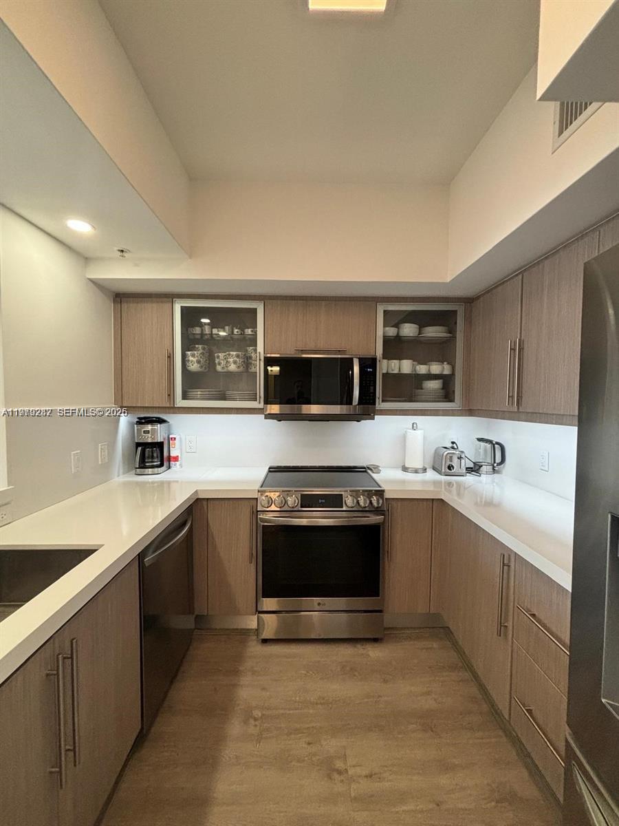 888 Douglas Road, Unit 1002 Coral Gables, FL 33134 - Photo 13 of 34 a large kitchen with stainless steel appliances granite countertop a sink and dishwasher a stove top oven with wooden floor