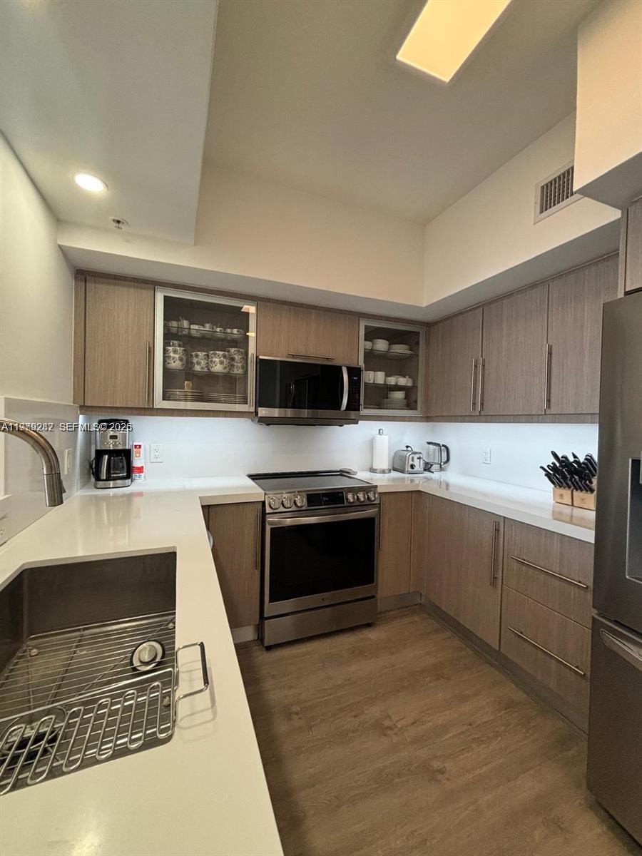 888 Douglas Road, Unit 1002 Coral Gables, FL 33134 - Photo 14 of 34 a kitchen with stainless steel appliances granite countertop a sink and stove top oven