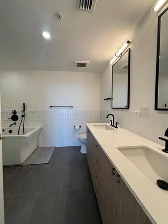 a bathroom with a double vanity sink mirror and bathtub