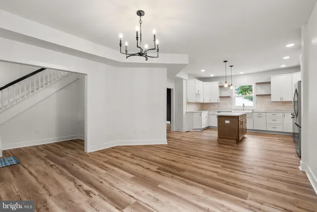 a view of an empty room with window and chandelier fan