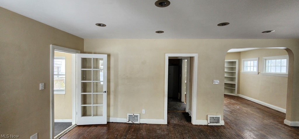3599 Grosvenor Road Cleveland, OH 44118 - Photo 3 of 25 Spare room with arched walkways, healthy amount of natural light, and dark wood-style floors
