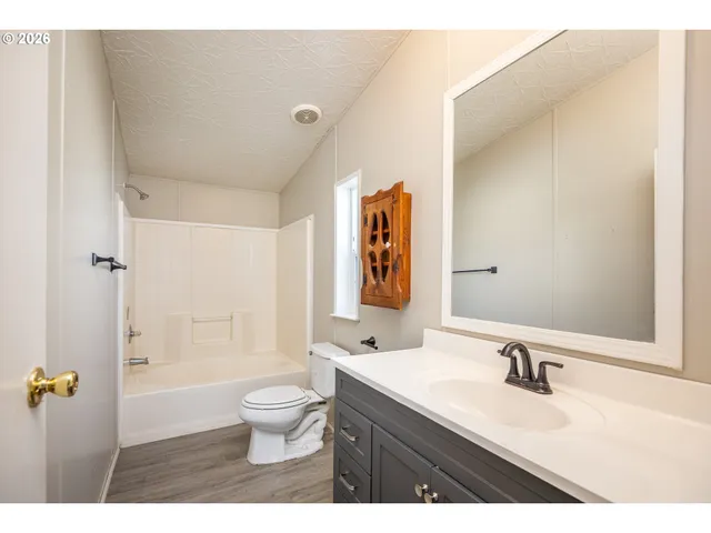 a bathroom with a granite countertop sink a toilet a mirror and shower