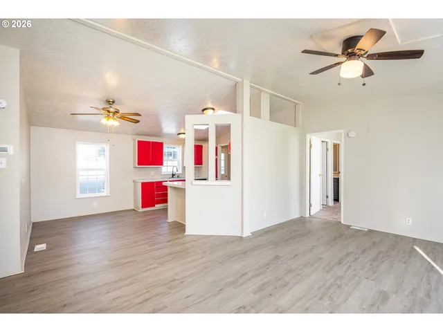 a view of an empty room with wooden floor and white walls