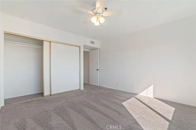 an empty room with windows and chandelier fan