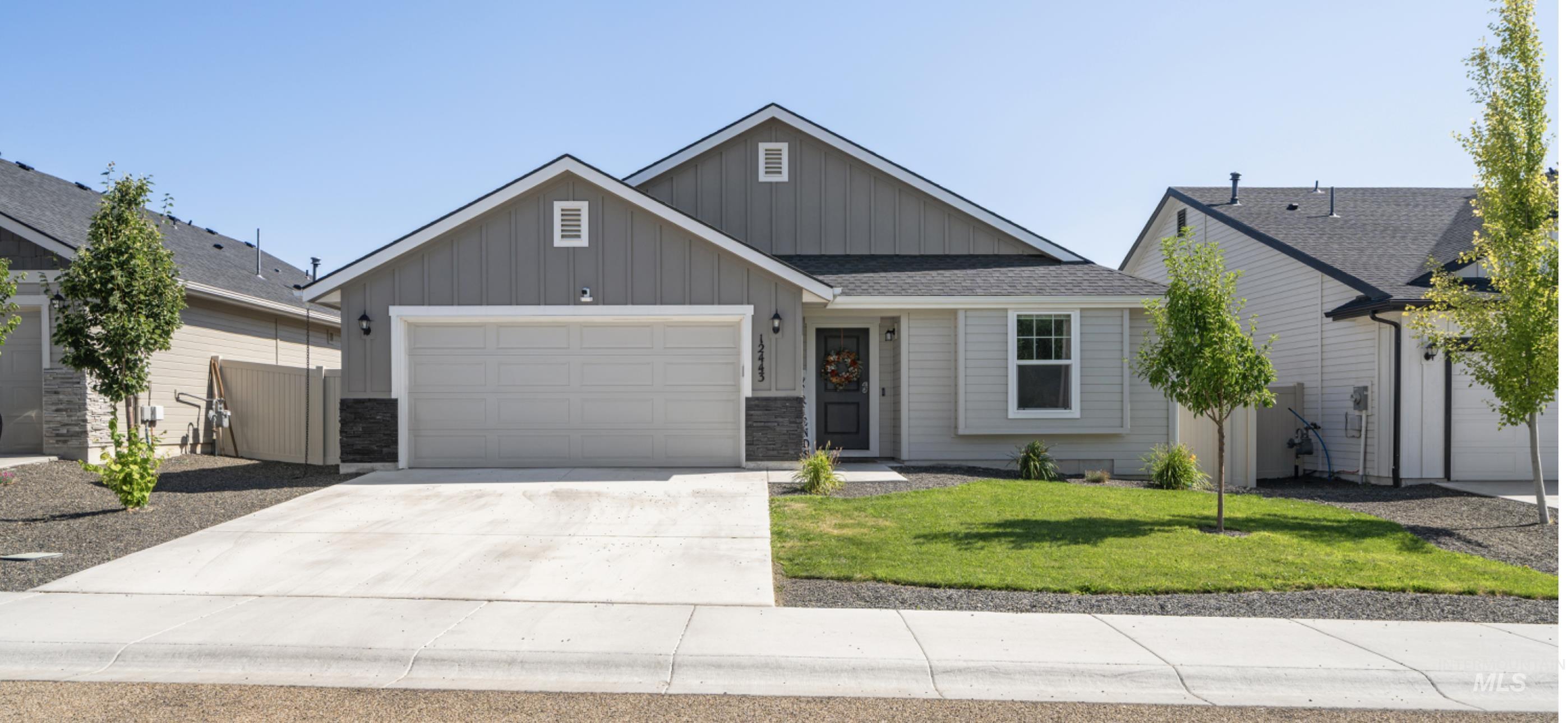 12443 Varga Street Caldwell, ID 83607 - Photo 1 of 27 View of front facade with board and batten siding, an attached garage, driveway, a front yard, and stone siding