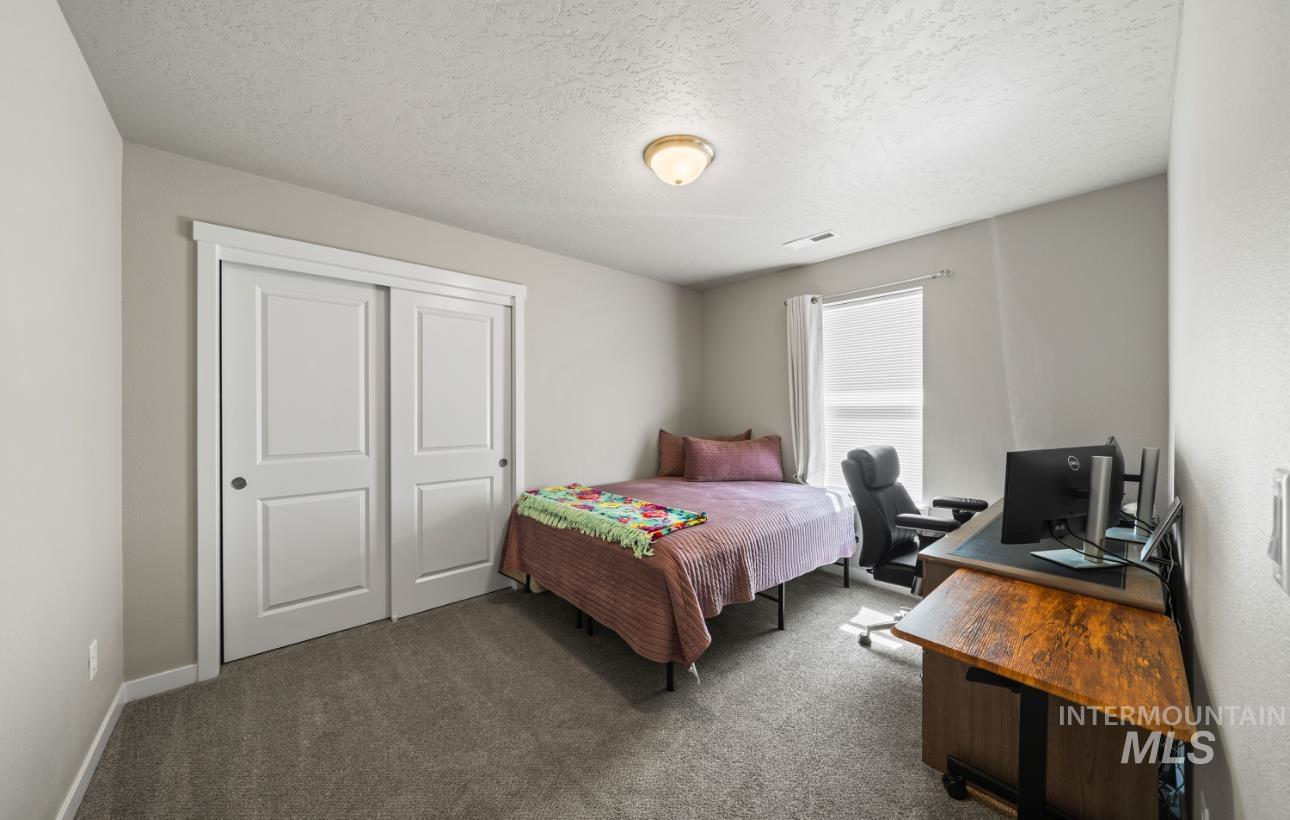 12443 Varga Street Caldwell, ID 83607 - Photo 19 of 27 Bedroom with dark carpet, a desk, a textured ceiling, and a closet