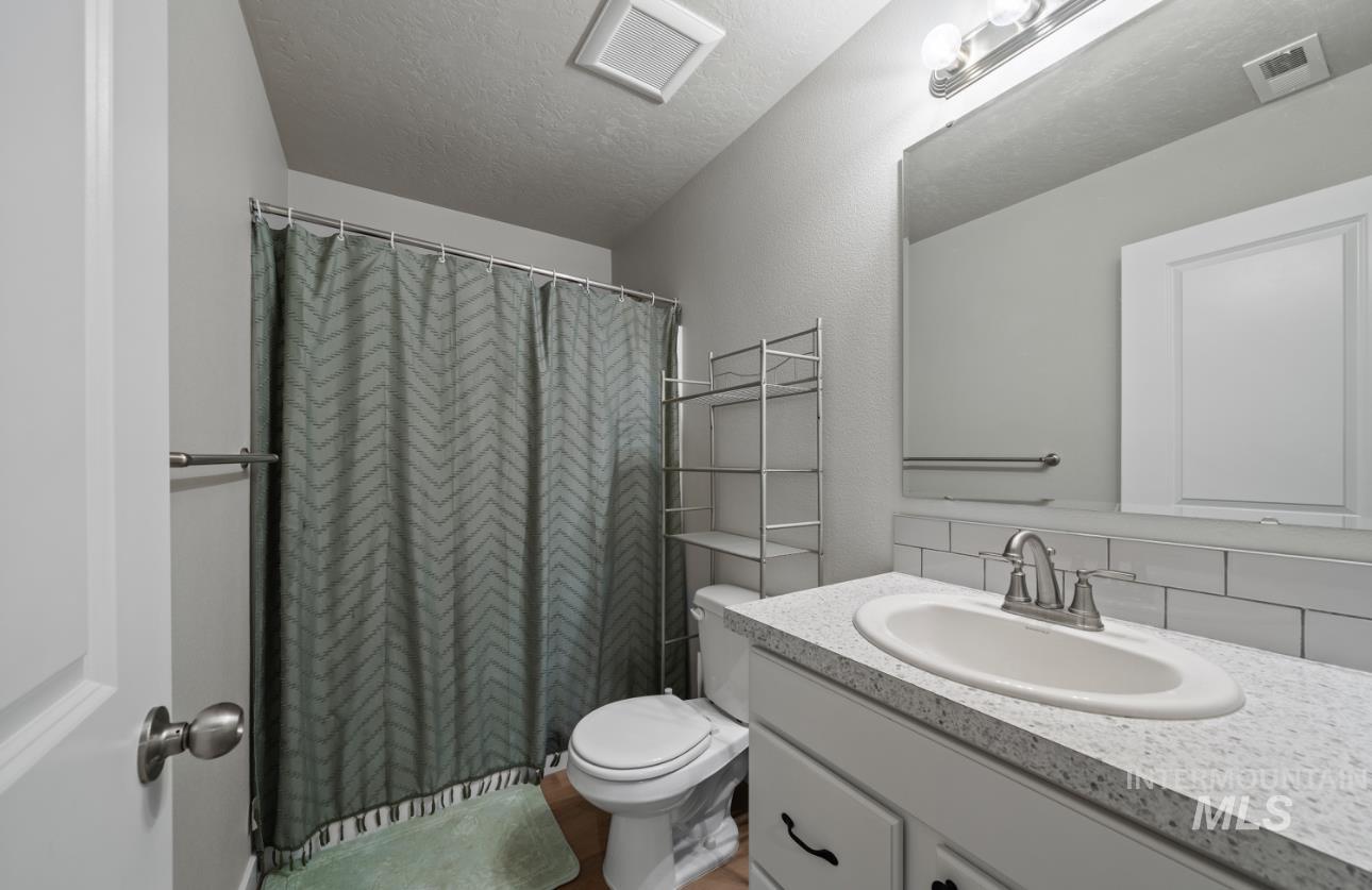 12443 Varga Street Caldwell, ID 83607 - Photo 21 of 27 Full bathroom featuring vanity, a textured ceiling, a shower with curtain, and tasteful backsplash