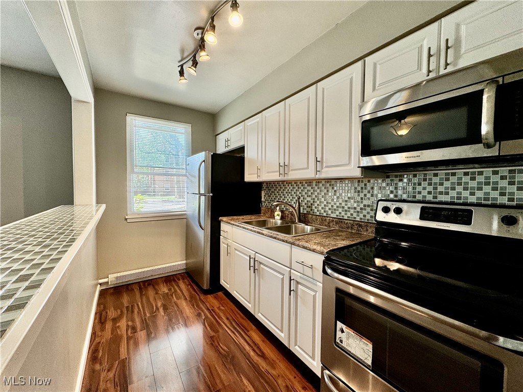 13805 Cedar Road, Unit 103C Cleveland, OH 44118 - Photo 7 of 18 Kitchen featuring dark wood-style floors, appliances with stainless steel finishes, tasteful backsplash, sink, and white cabinetry