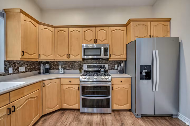 11789 Nicklaus Road Sandy, UT 84092 - Photo 12 of 58 Kitchen with stainless steel appliances, light countertops, light wood finish cabinets, and light wood finished floors