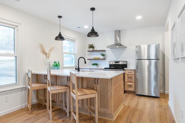 a kitchen with stainless steel appliances granite countertop a sink a stove a refrigerator and island with wooden floor